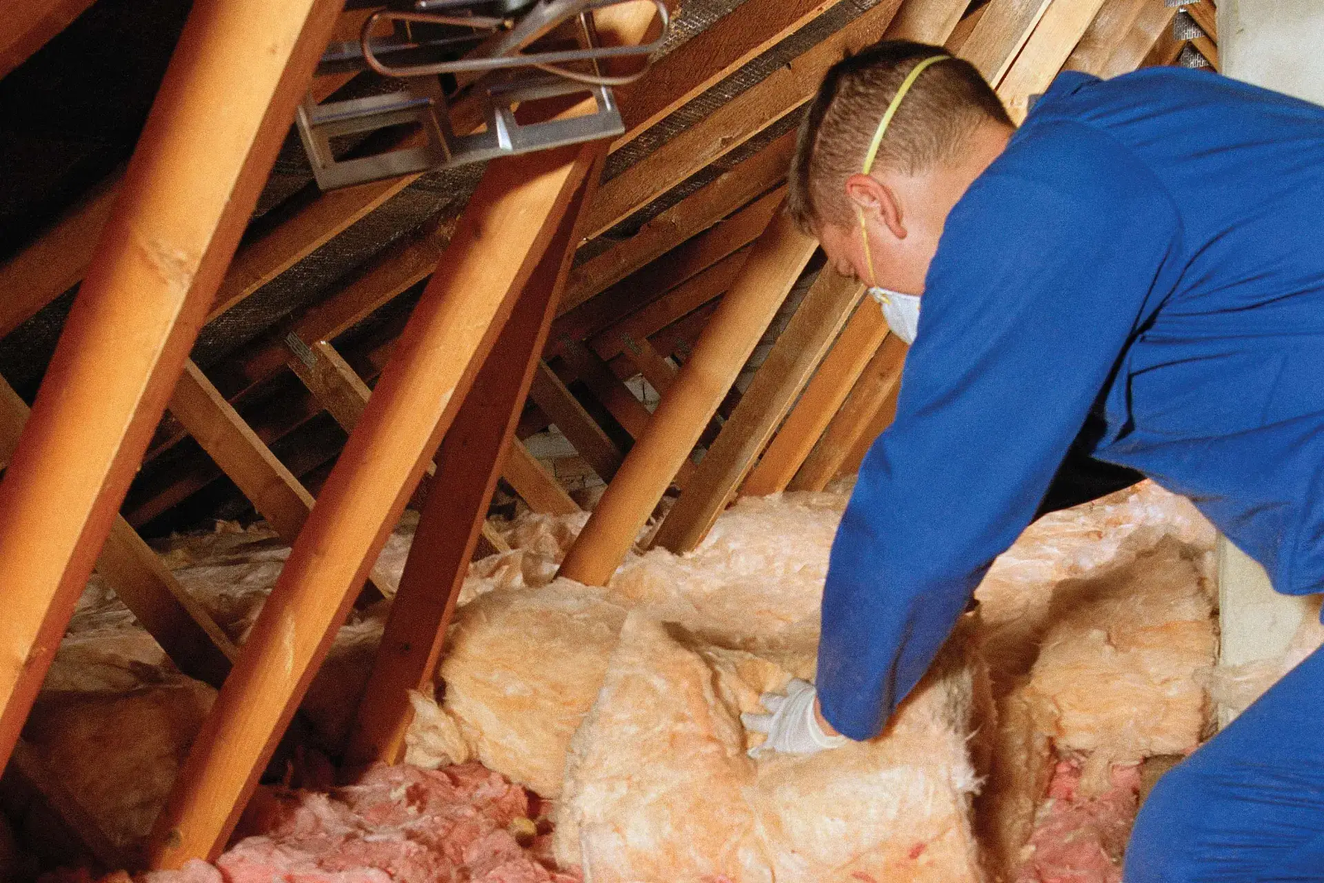 Person installing insulation as part of retrofitting to improve energy efficiency in a building.