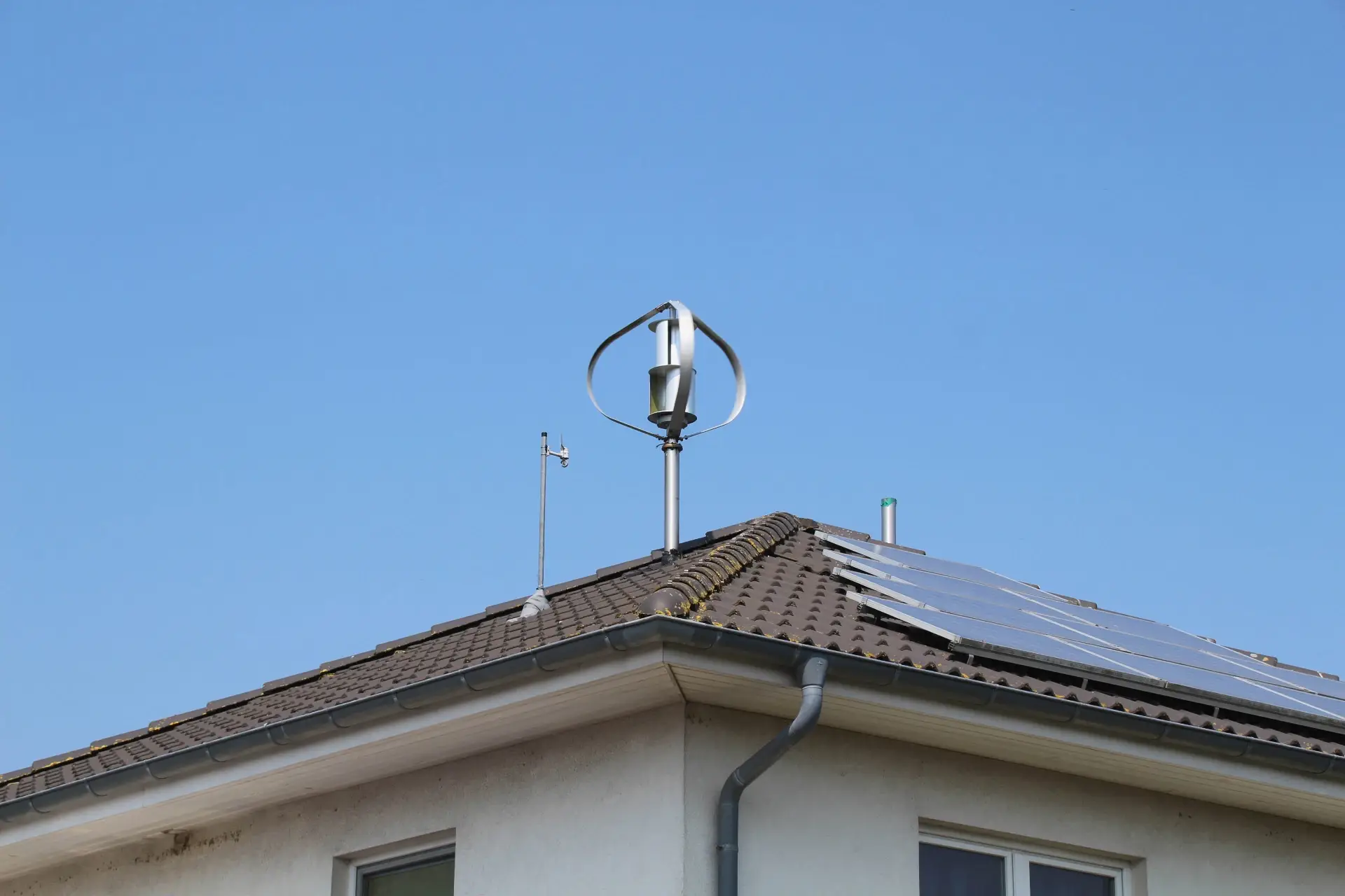 Roof-mounted vertical-axis wind turbine installed on a residential home with solar panels.