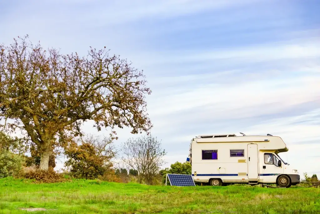 Portable solar panels set up next to a campervan in a green field, providing renewable energy in a remote location.