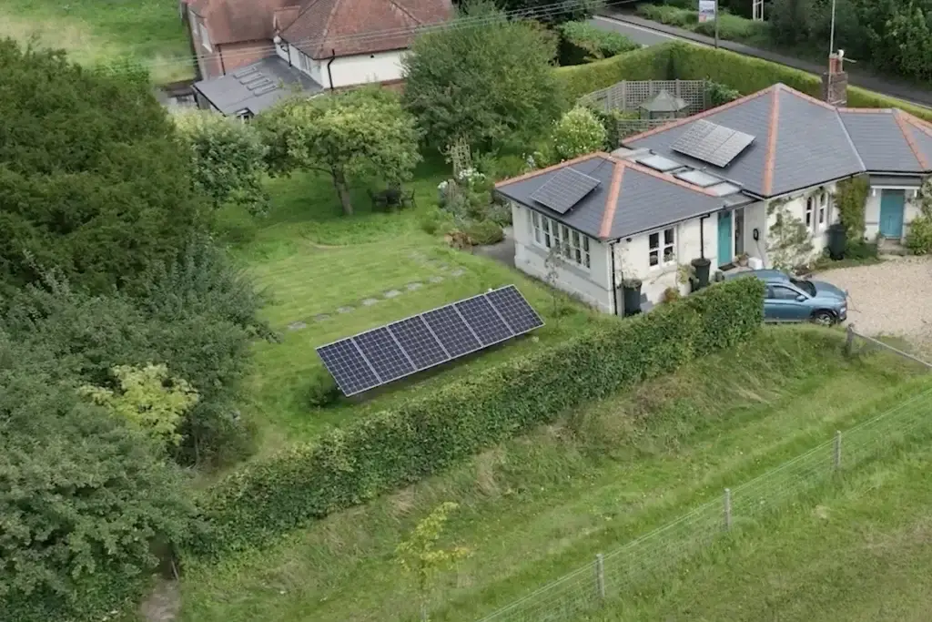 Aerial view of a house with portable solar panels installed in the garden and on the roof.